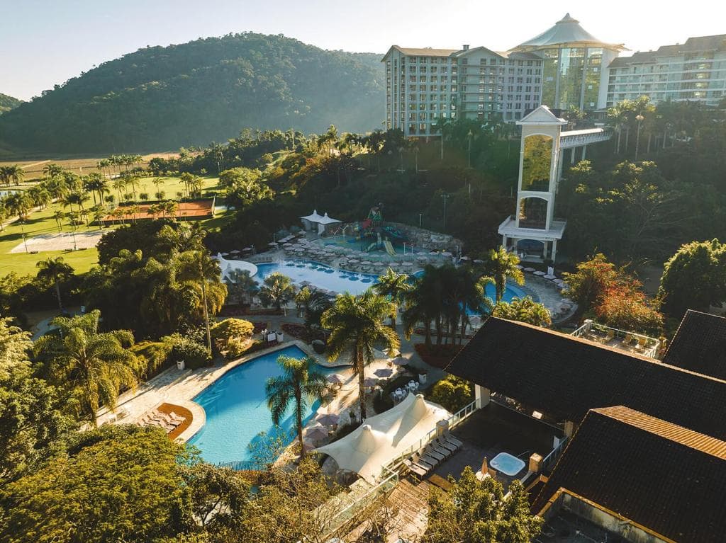 Vista aérea do Fazzenda Park Resort, com as piscinas, o parque aquático, os prédios do hotel e a mata ao fundo